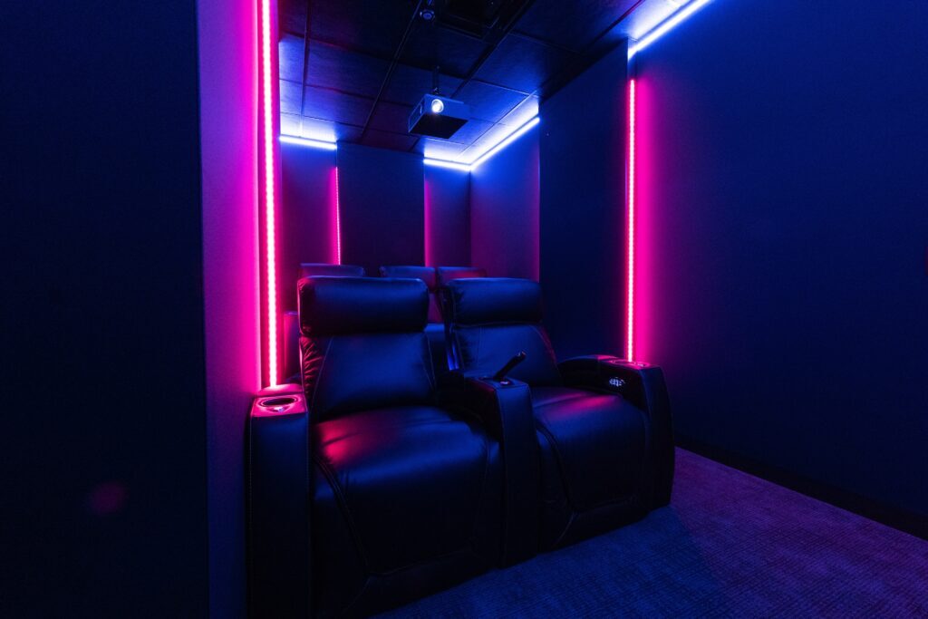 Luxury home theater seating with ambient purple and blue LED lighting, designed for a premium viewing experience.